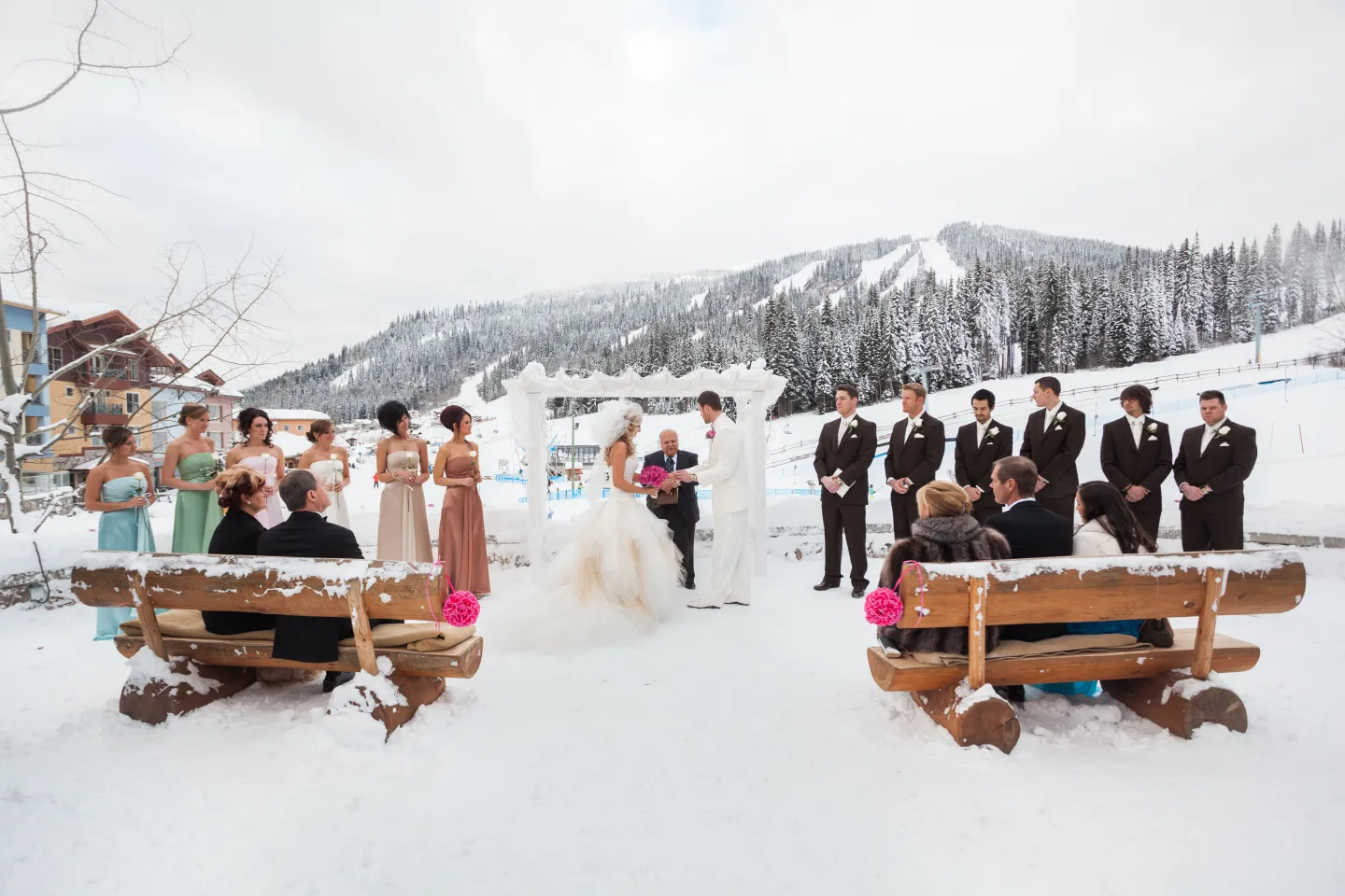 A wedding ceremony takes place outside in winter at a ski resort