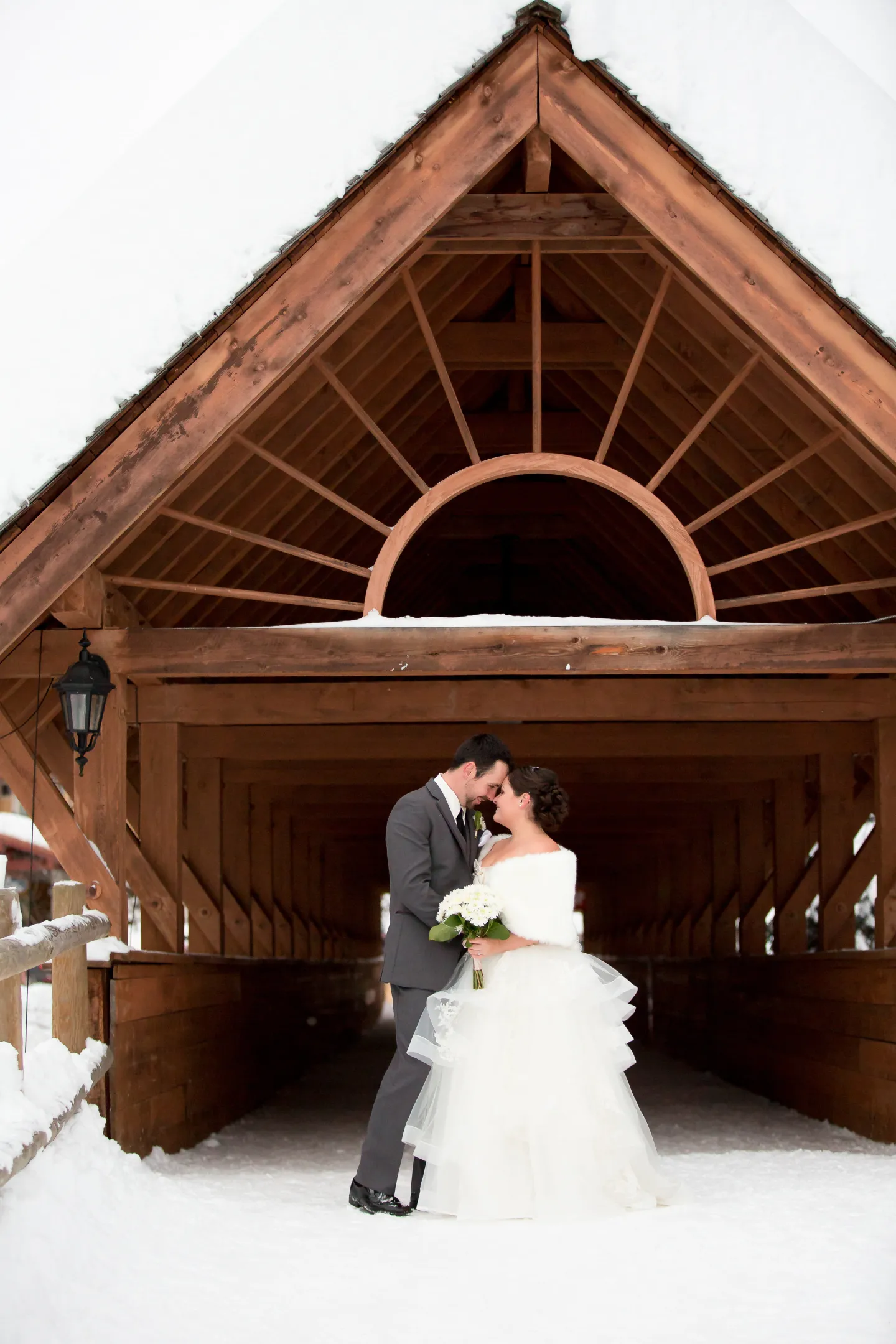 A bride and groom stand beneath a bridge archway