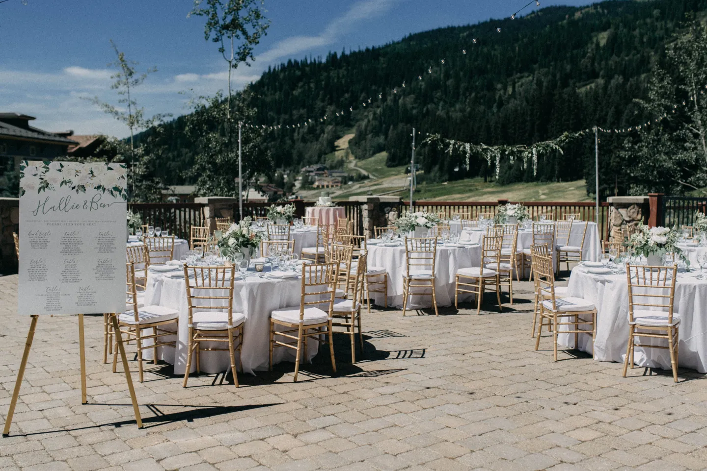 A wedding reception with round tables and chairs set on a resort terrace in summer