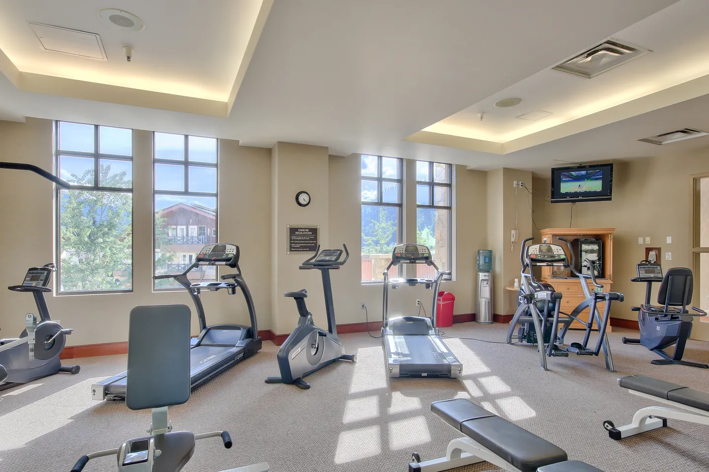 An indoor hotel fitness room with various treadmills and exercise machines