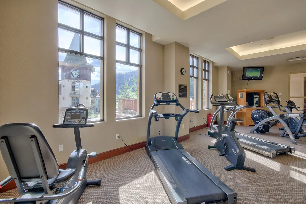 An indoor hotel fitness room with various treadmills and exercise machines