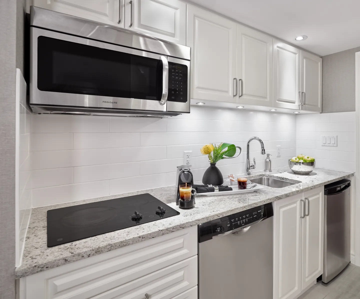 A hotel kitchenette with modern appliances and bright furnishings