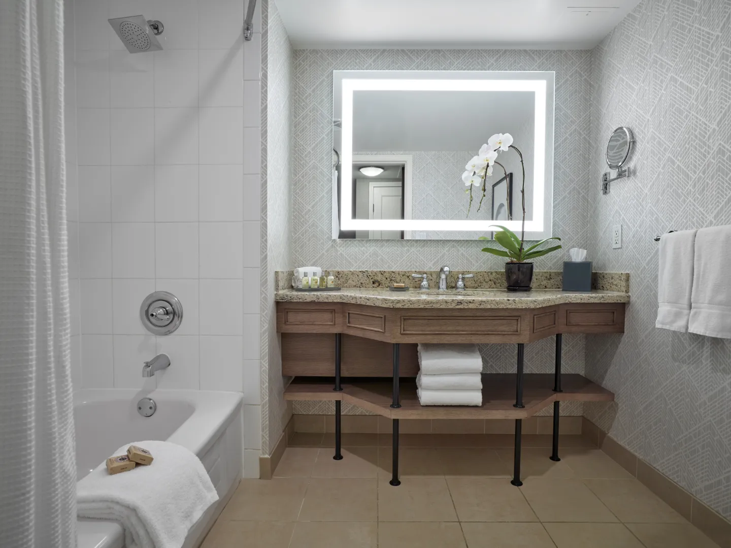View of a bathroom facing a sink and mirror, with a bath tub and shower on the left