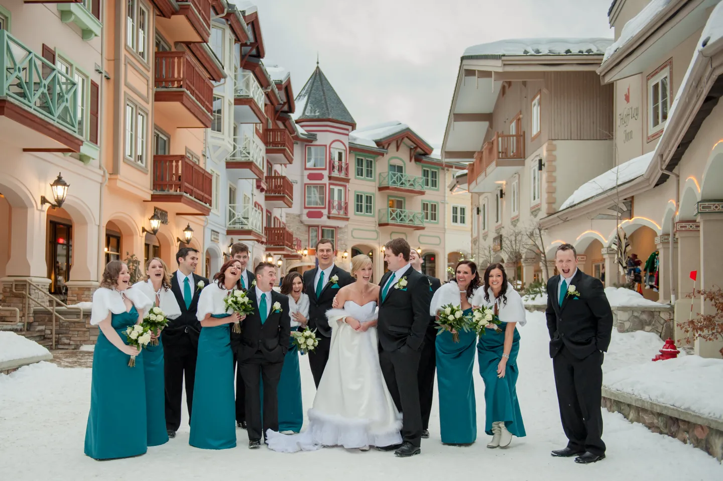 A bridal party pose for a photo in a winter village stroll