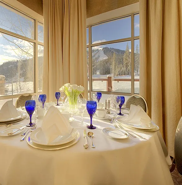 A grand hotel dining hall with windows viewing out to a ski resort