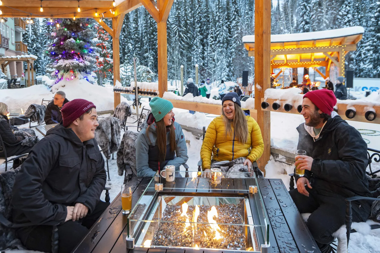 Four friends have drinks on an outdoor patio in winter