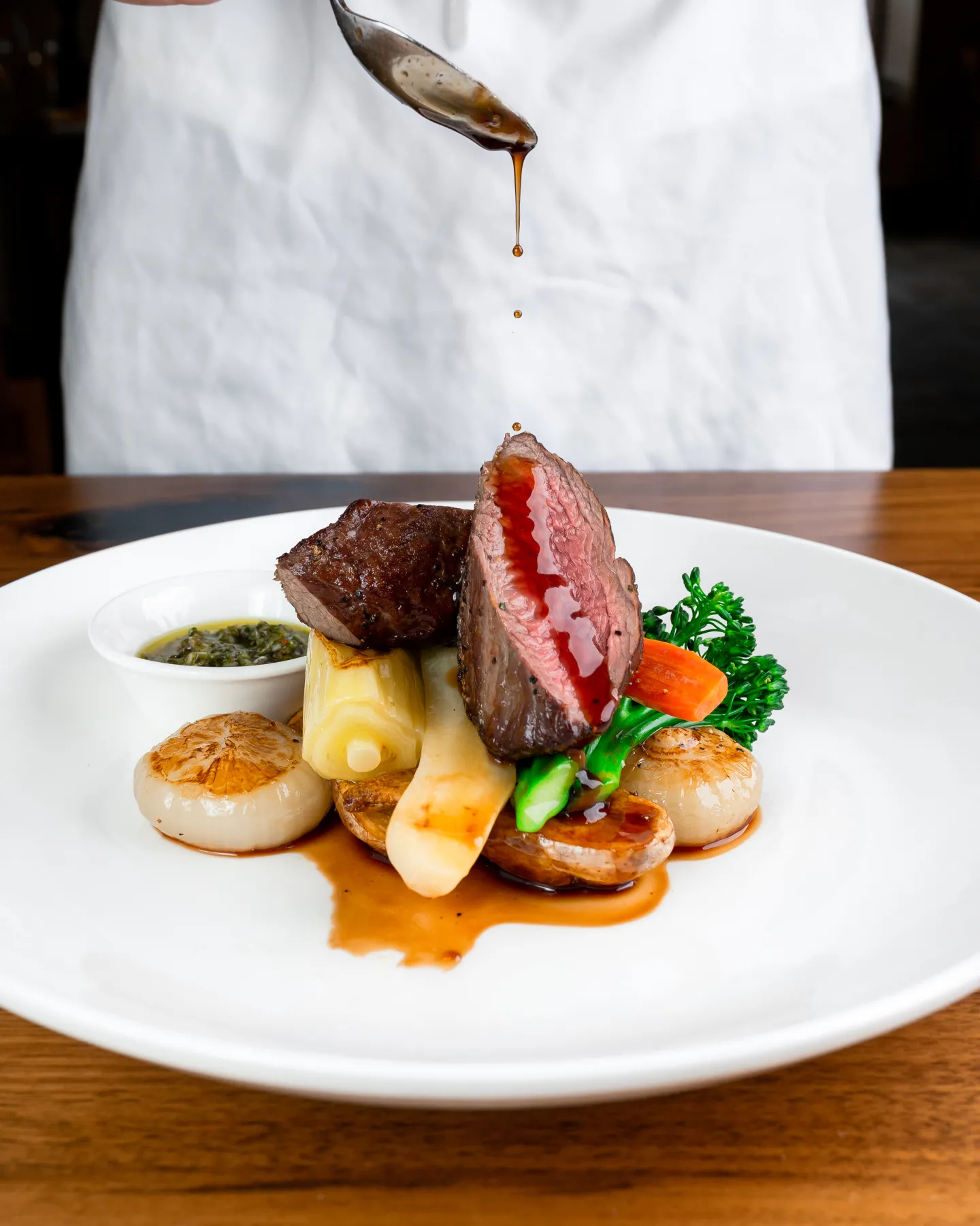 A chef drizzles sauce over a plate of food