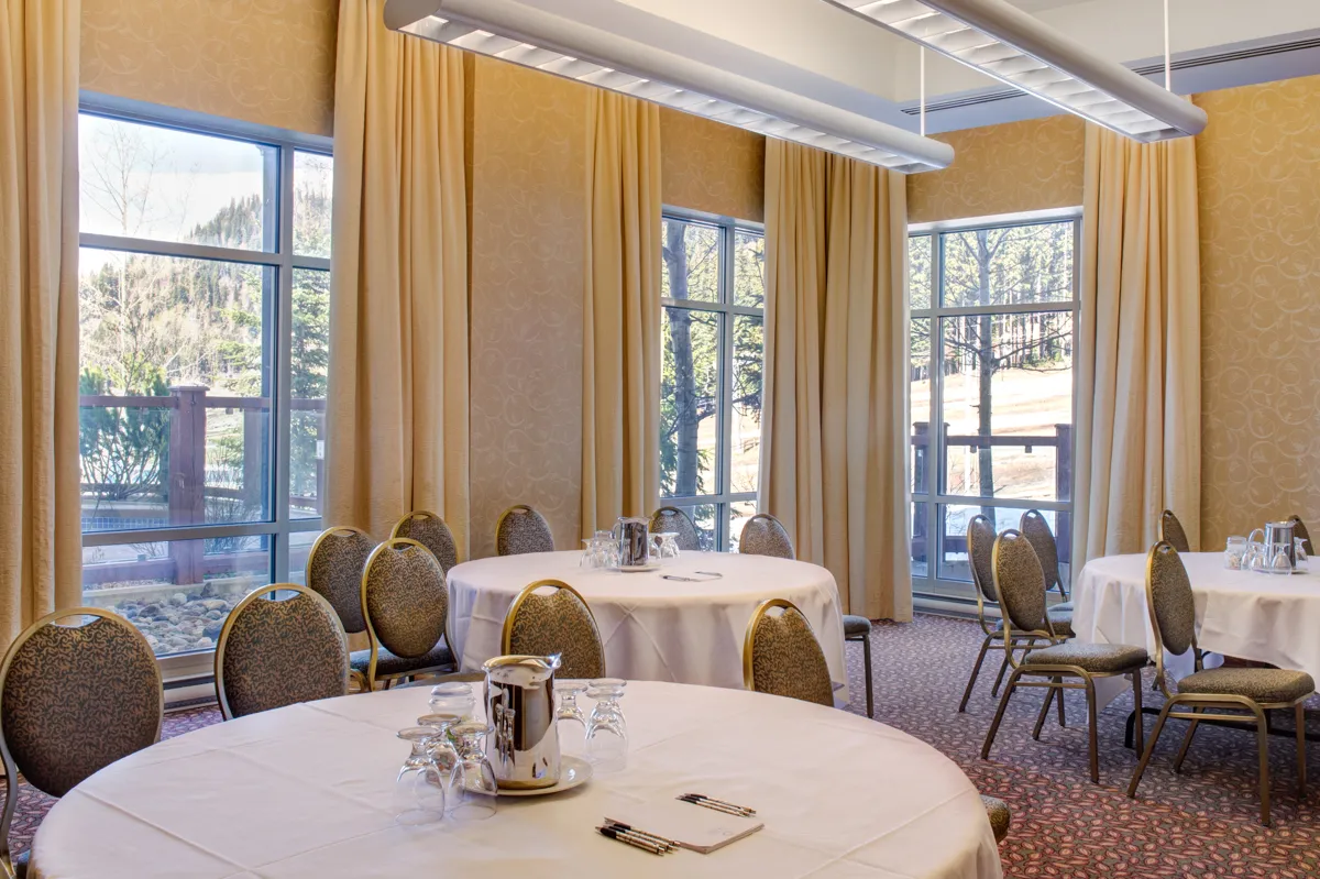A grand hotel event room set with round tables and chairs
