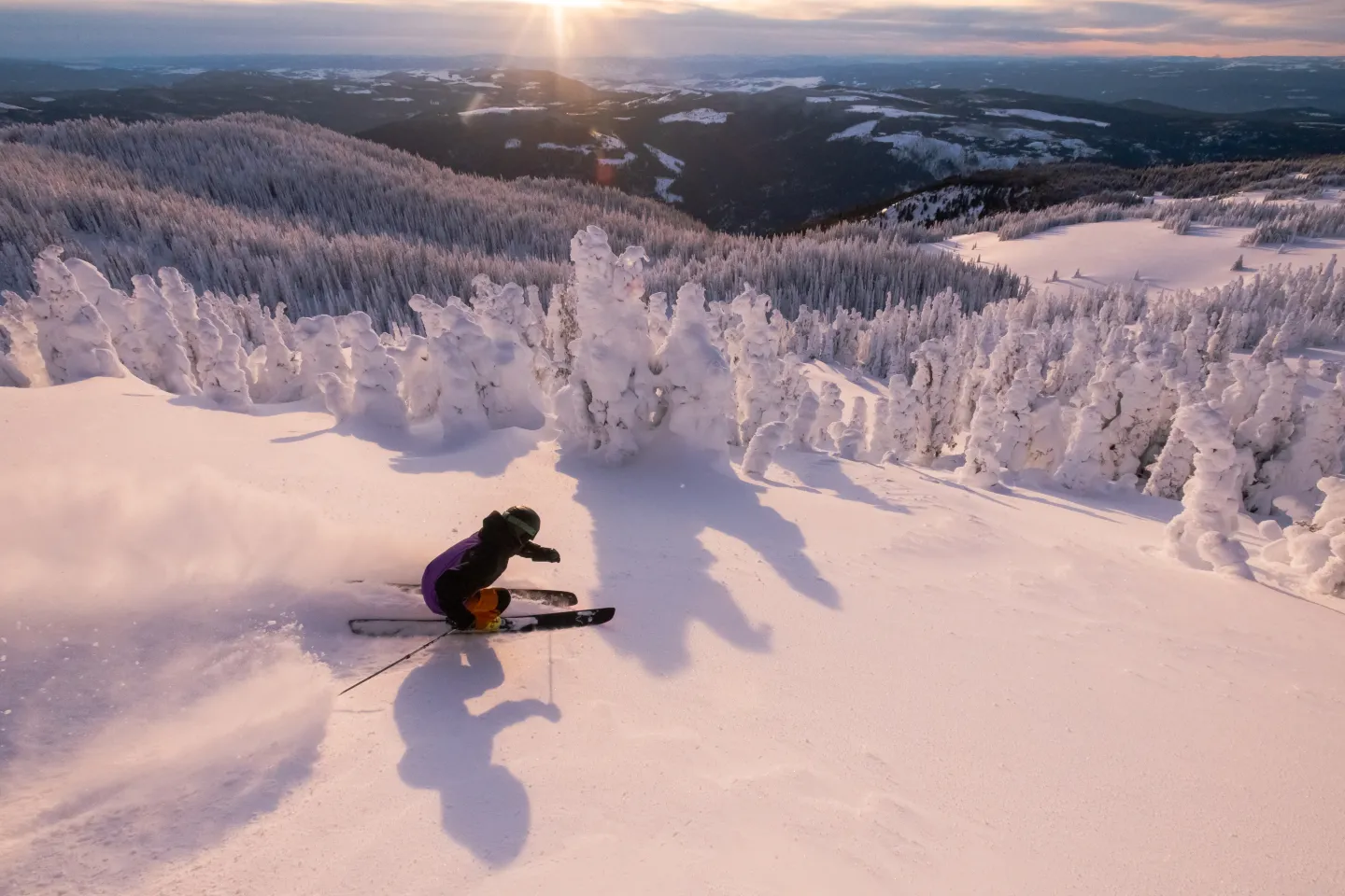 Skier in powder with sunset and mountain views