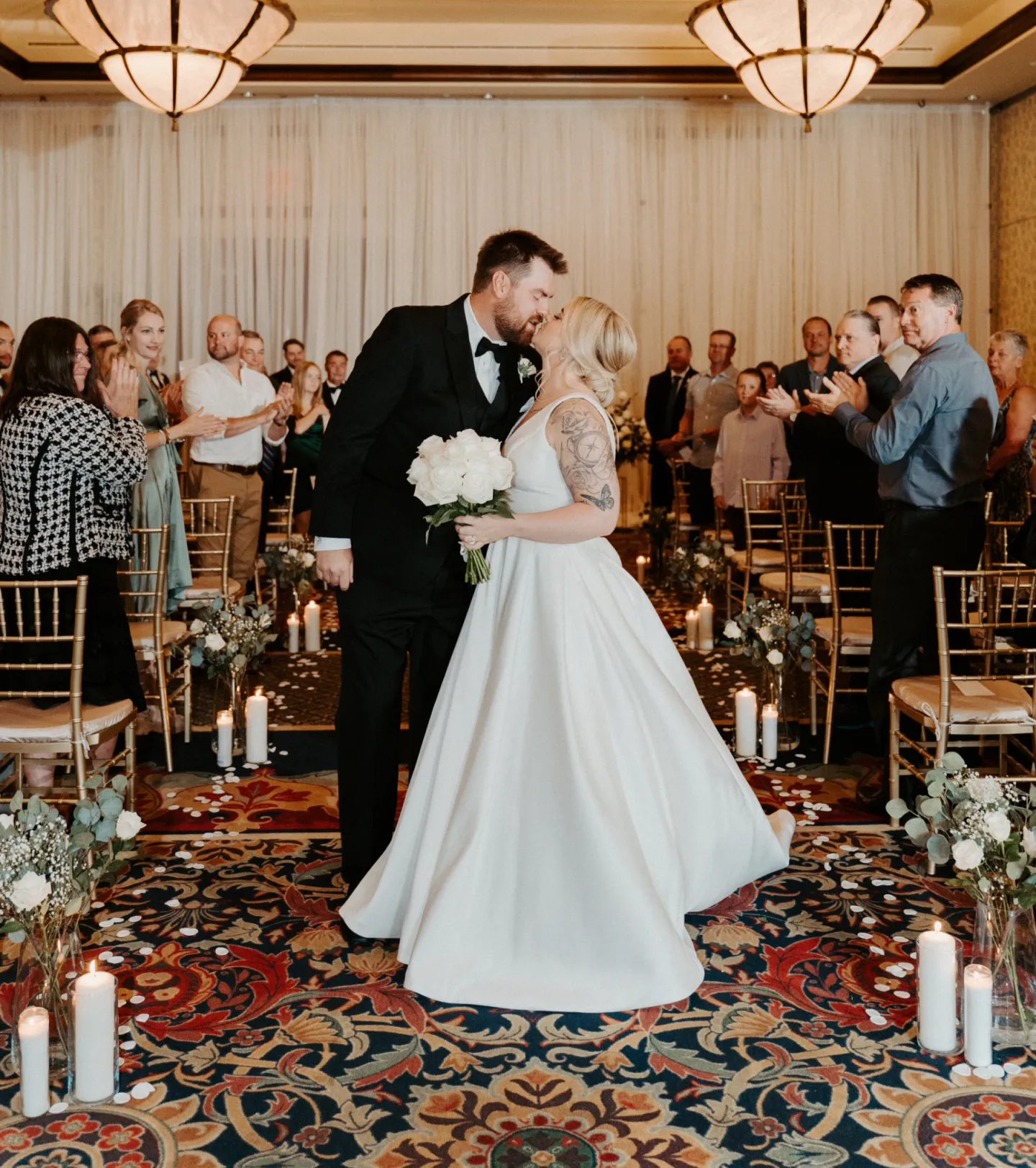 Bride and Groom kissing in the aisle with people around them clapping