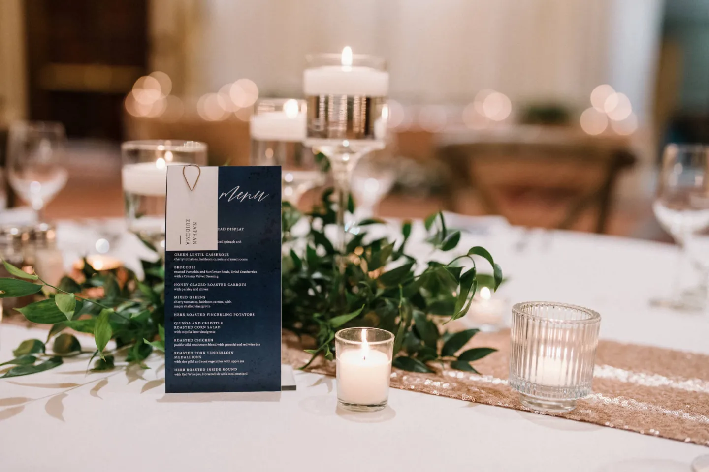 A table set up with candle and plant décor with a menu set up