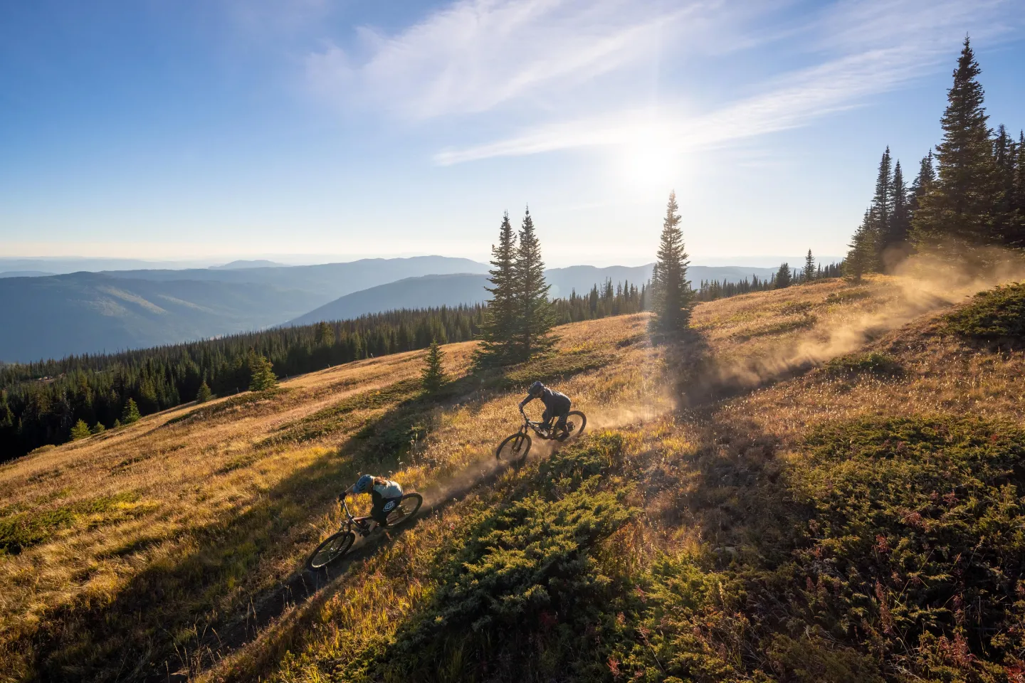 Two bikers riding down the mountain at sunset