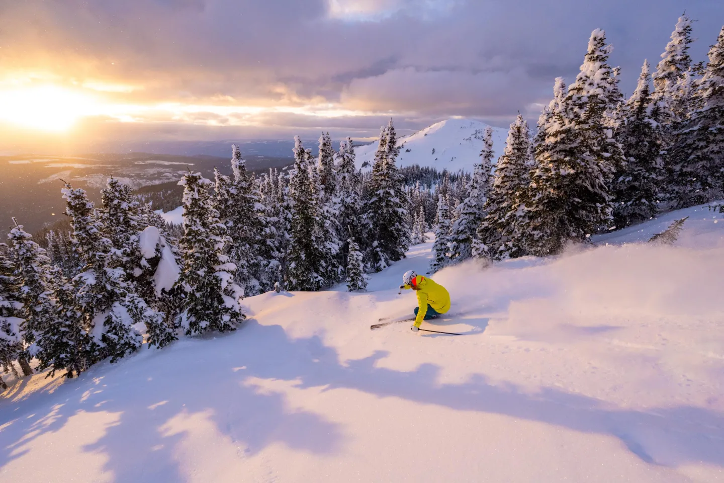 Skier in powder with the sun setting