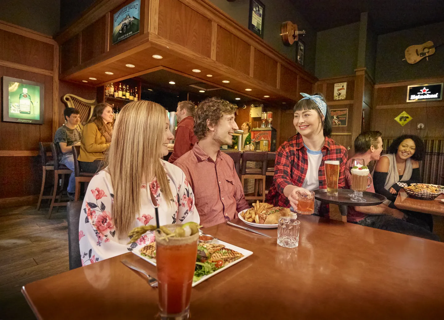 Two people sitting at a table being served food and drinks in a restaurant