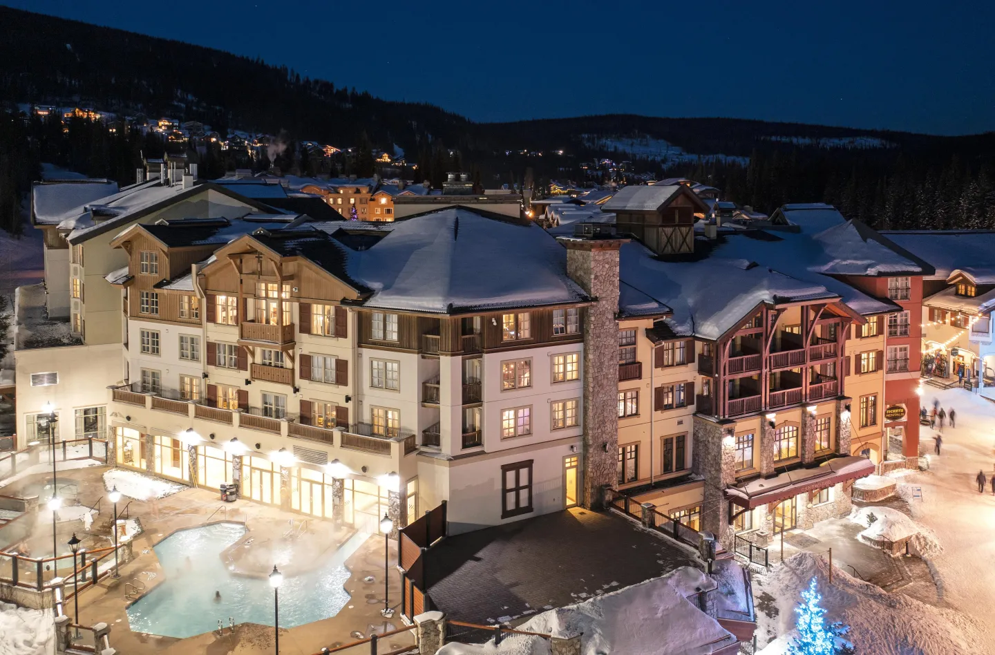 View of a hotel in the winter at night with a pool and village views