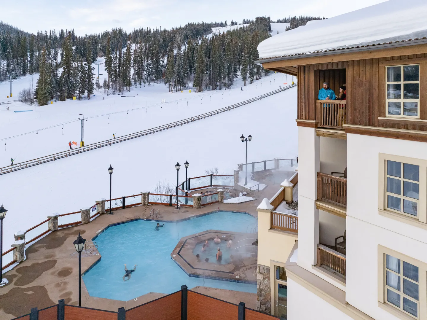 A view of a hotel and pool beside a ski hill in the winter