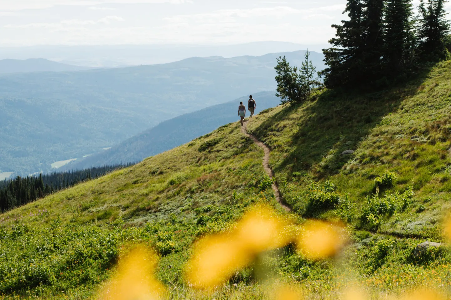 Two people hiking on a mountain with far mountain views