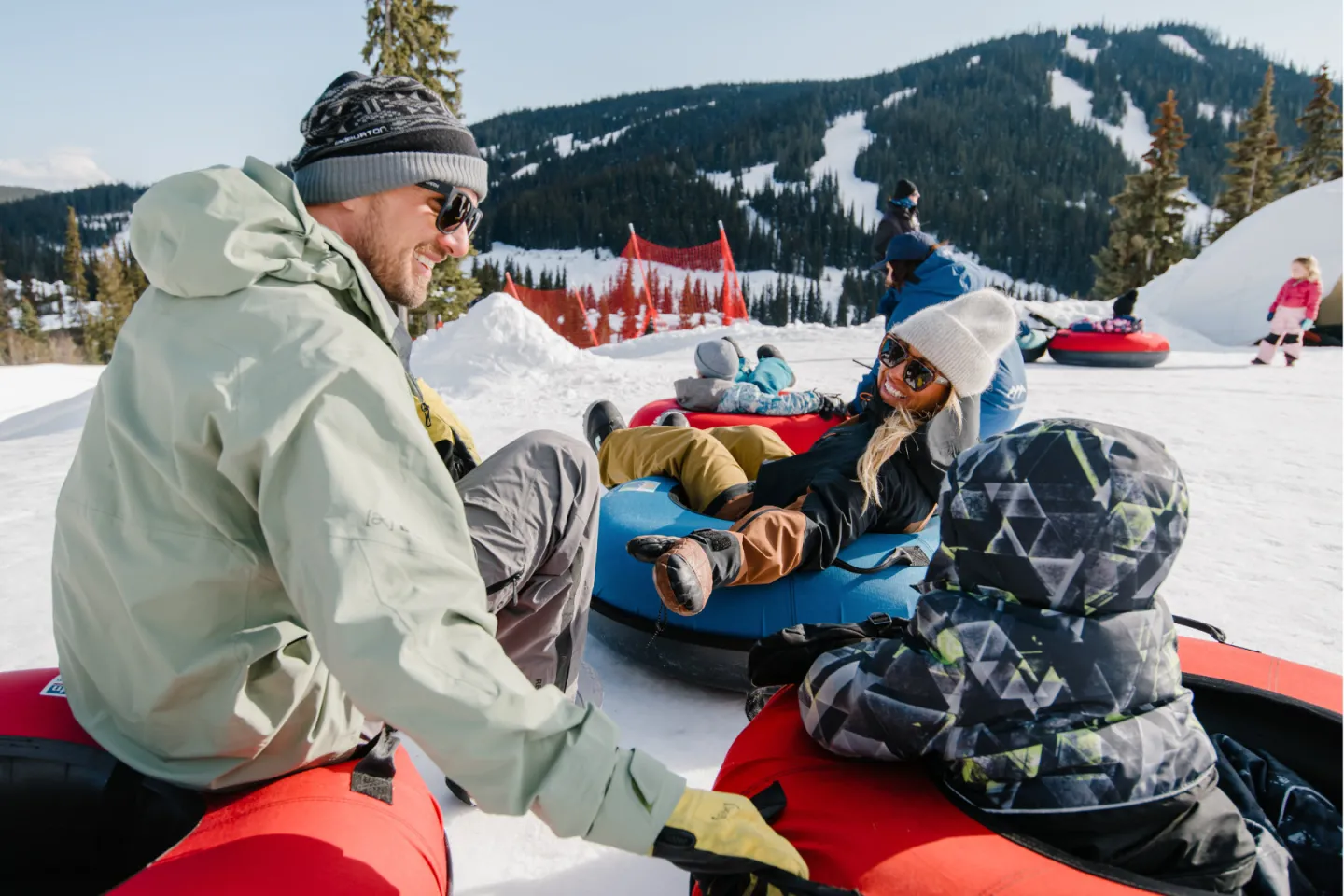 Three people on tubes smiling with mountains behind them