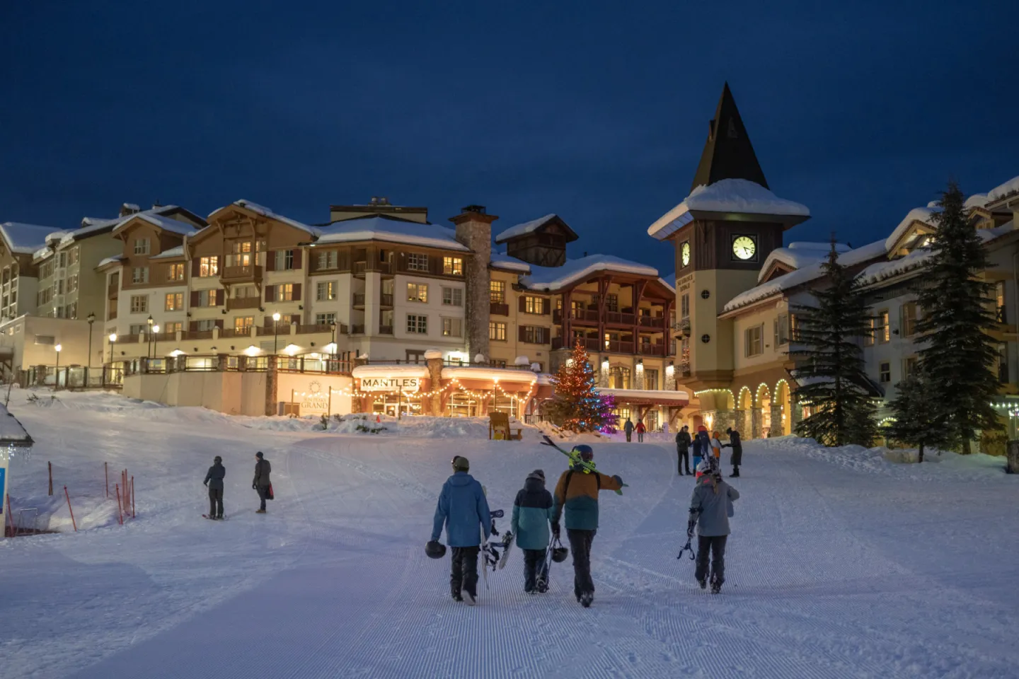 People walking slopeside on the mountain at night with the village in the background