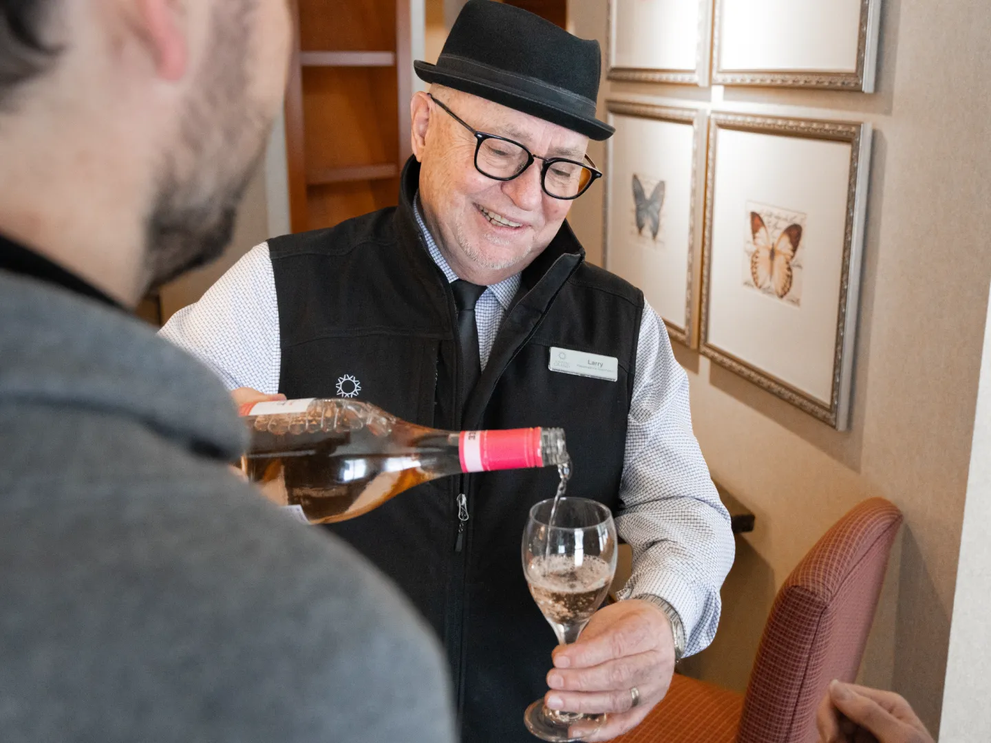 A man pouring wine into a glass with someone reaching for the glass