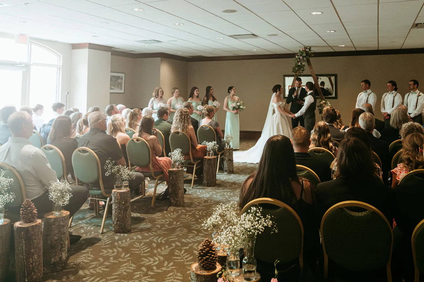 Wedding ceremony in a decorated indoor venue with guests seated facing the couple.