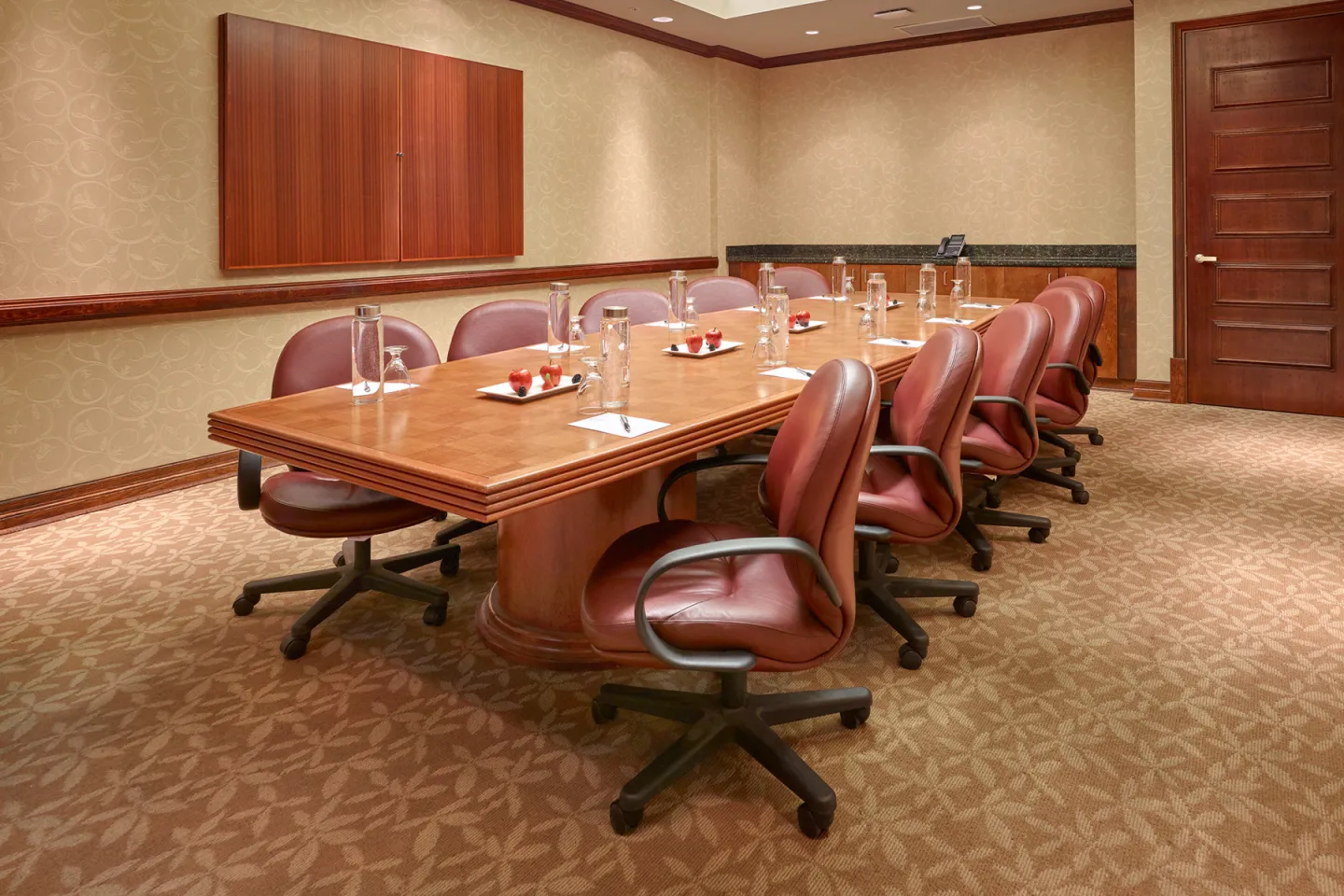 Modern conference room with a long table and leather chairs.