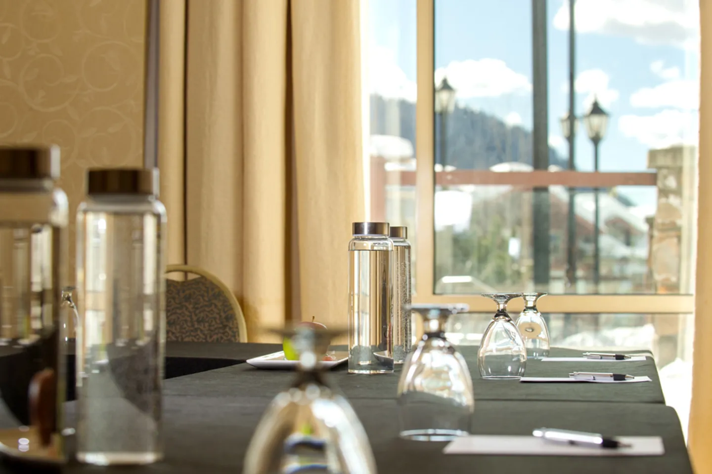 Conference table with bottles and glasses near a large window.