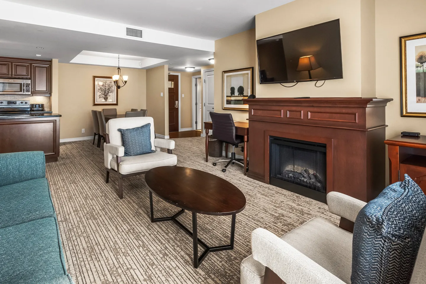 Spacious living room with a fireplace, sofa, armchairs, and a wall-mounted TV.