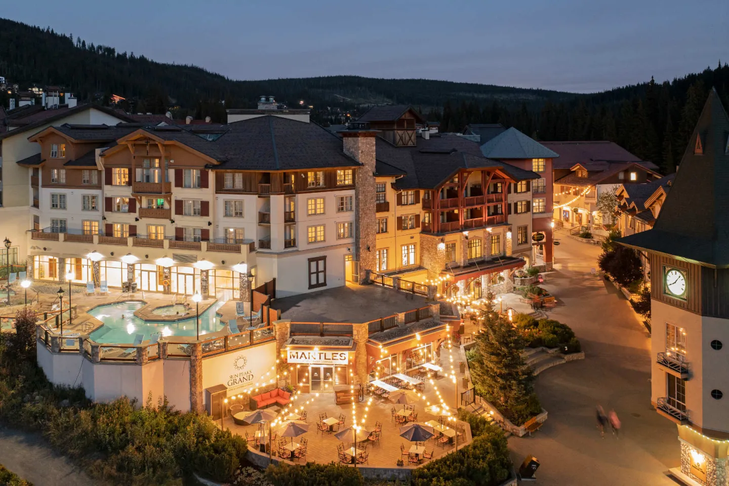 Alpine resort lit up at dusk with surrounding mountains.