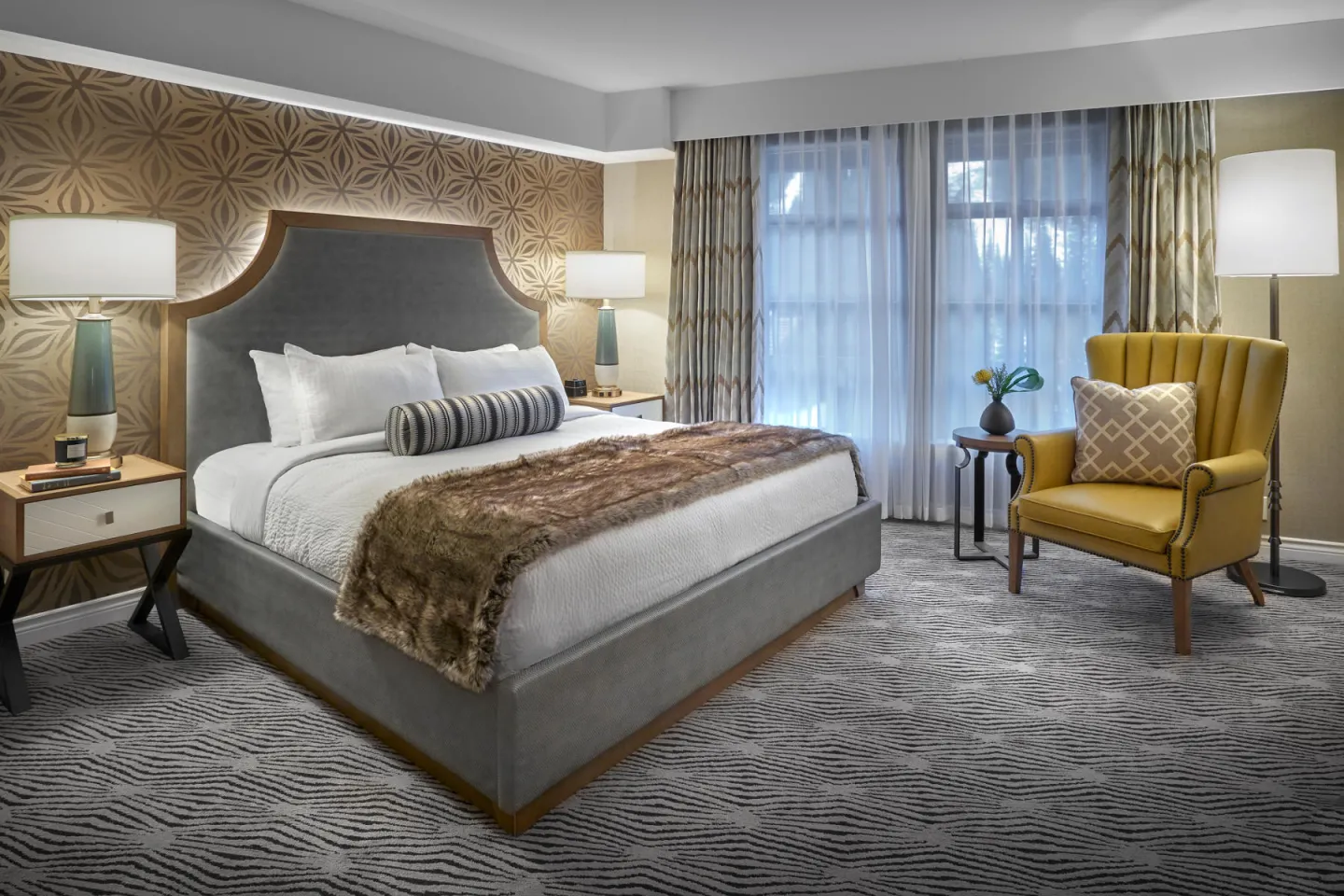 Elegant hotel room with a large bed, two lamps, and a yellow armchair by the window.