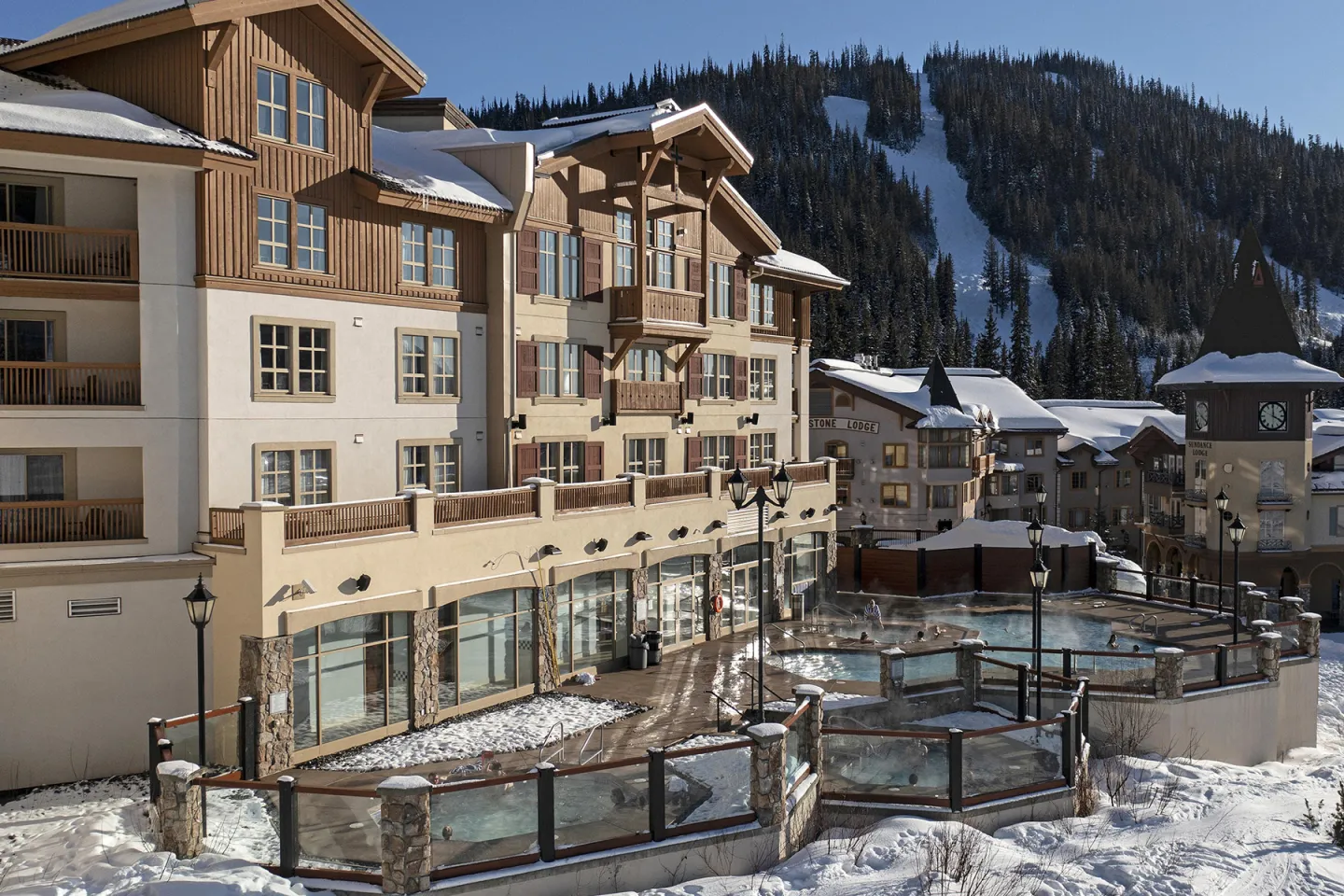Alpine resort with snow, wooden balconies, and nearby mountains.