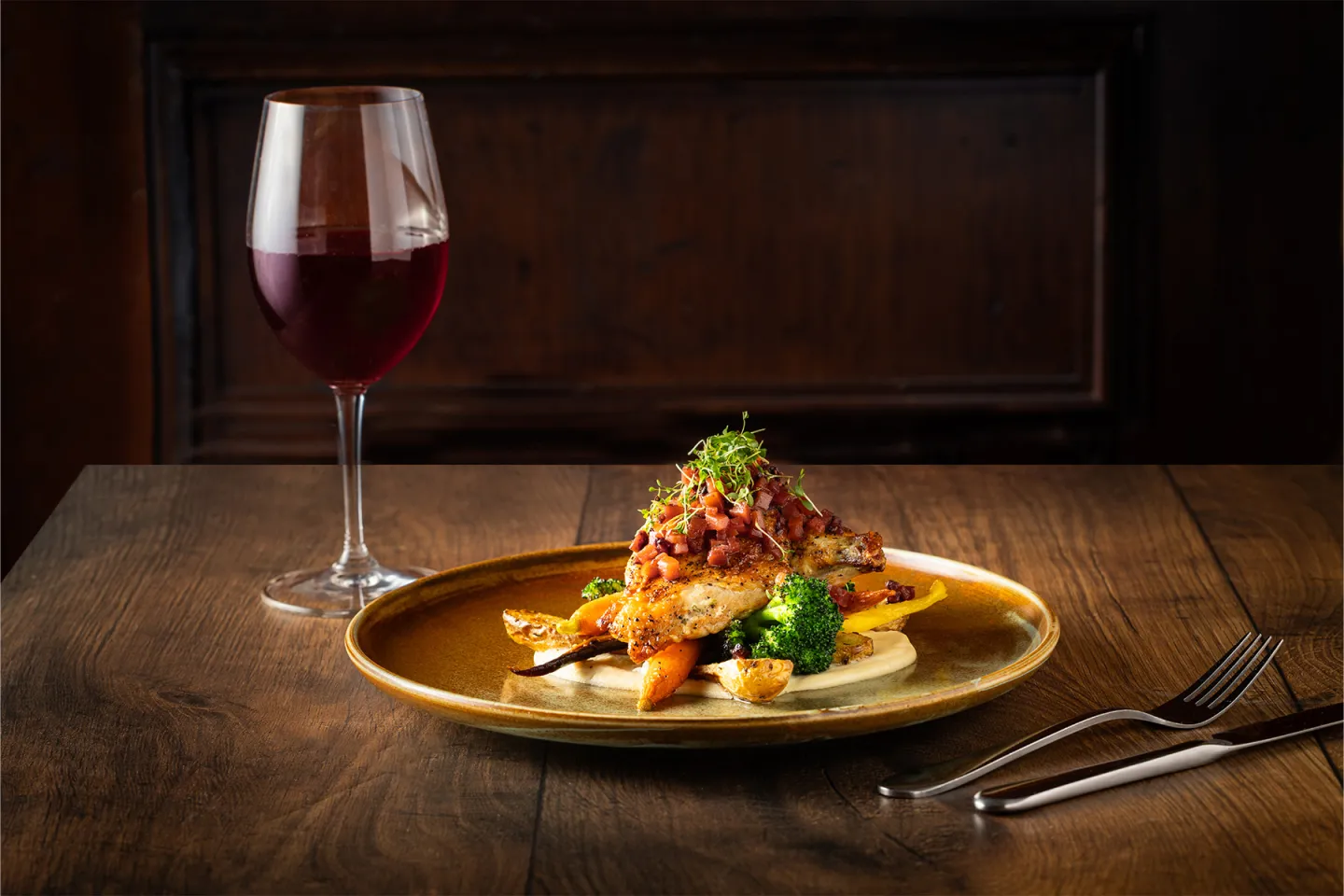 Chicken dish with vegetables and red wine on a wooden table.