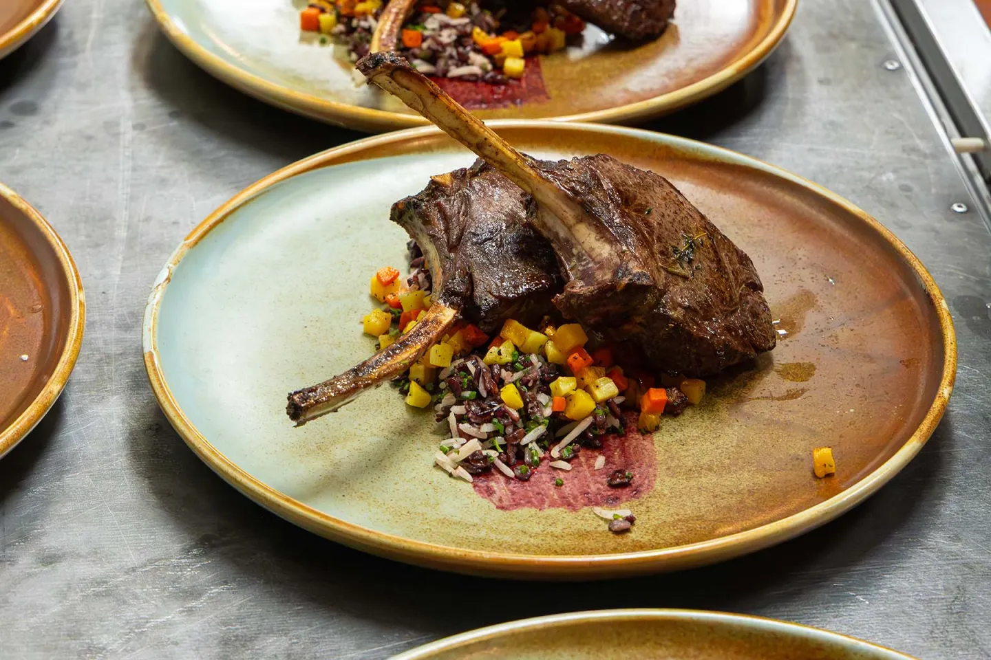 Grilled lamb chops with colorful diced vegetables on a rustic plate.