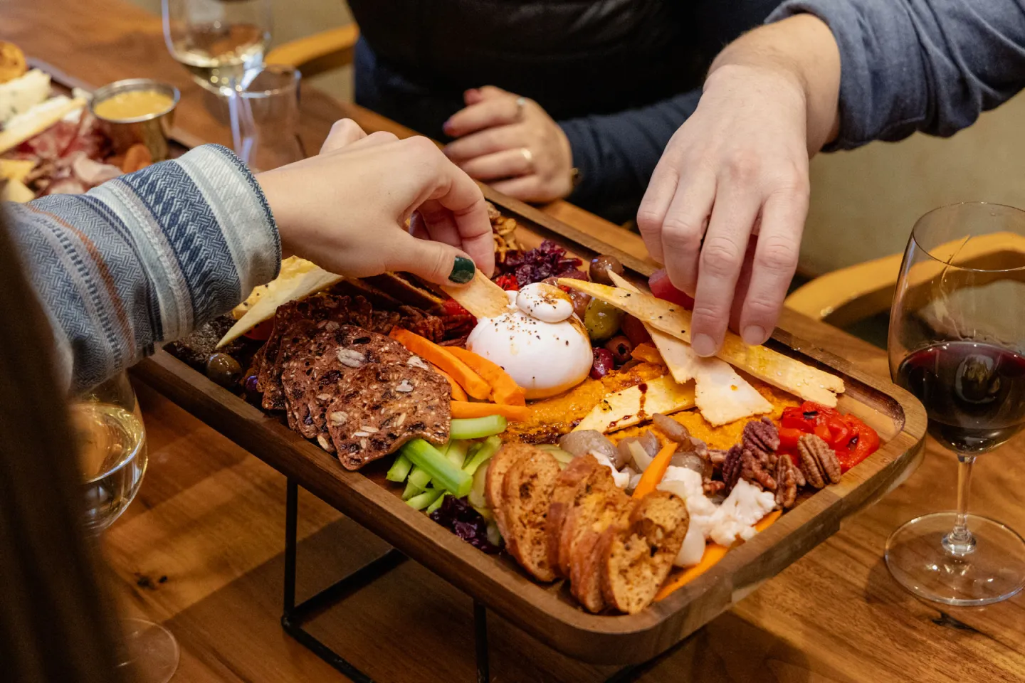 Charcuterie board with meats, cheese, and bread being shared by people.