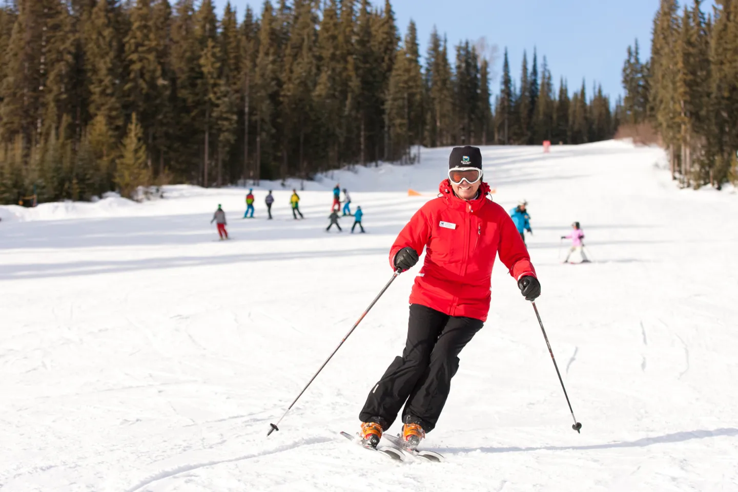 Olympic skier Nancy Greene in a red jacket on a snowy slope with trees and people in the background.