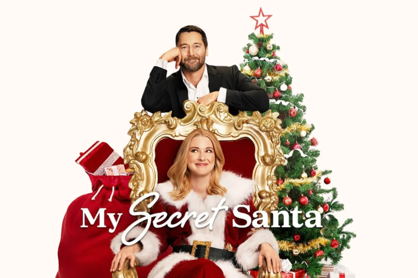 Man and woman posing by Christmas tree with gifts.