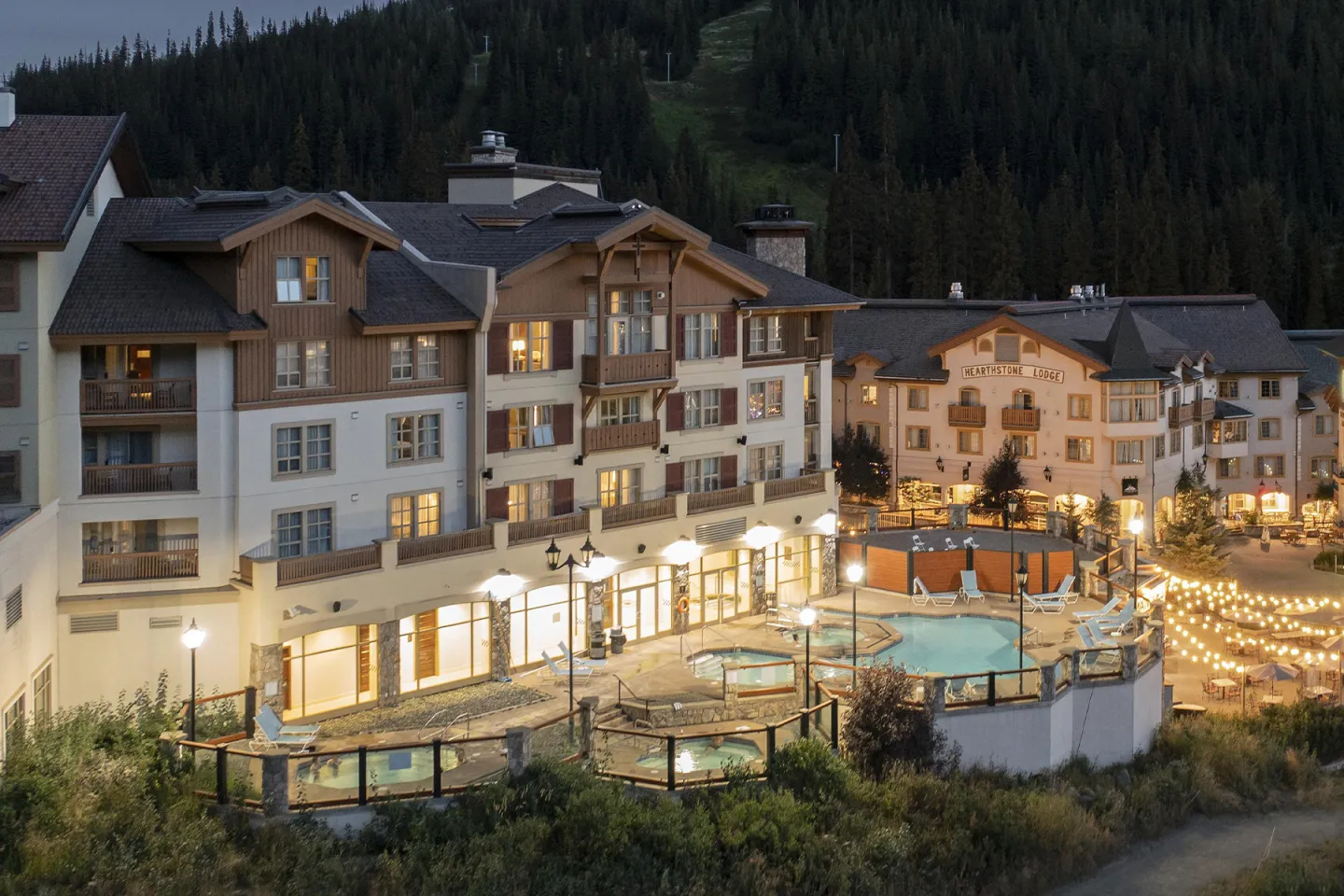 Mountain resort at dusk with lit pool area.