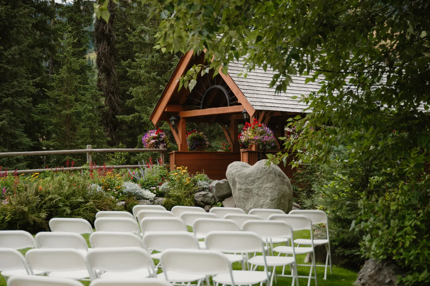 Outdoor wedding altar with white chairs and flowers.