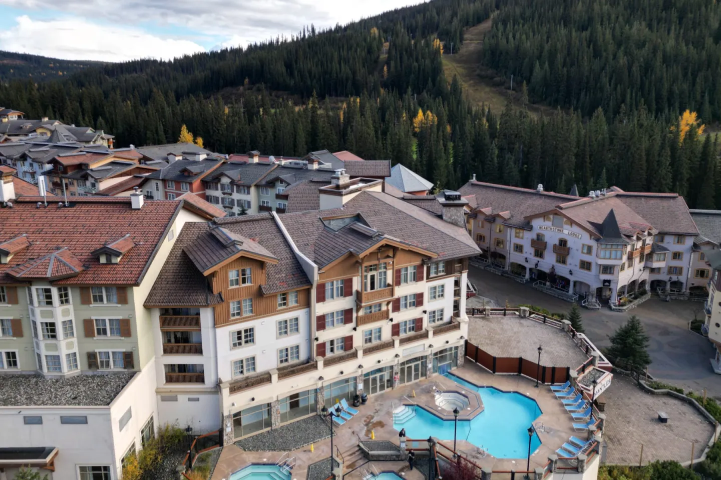 Alpine resort with pool, surrounded by forested mountains.