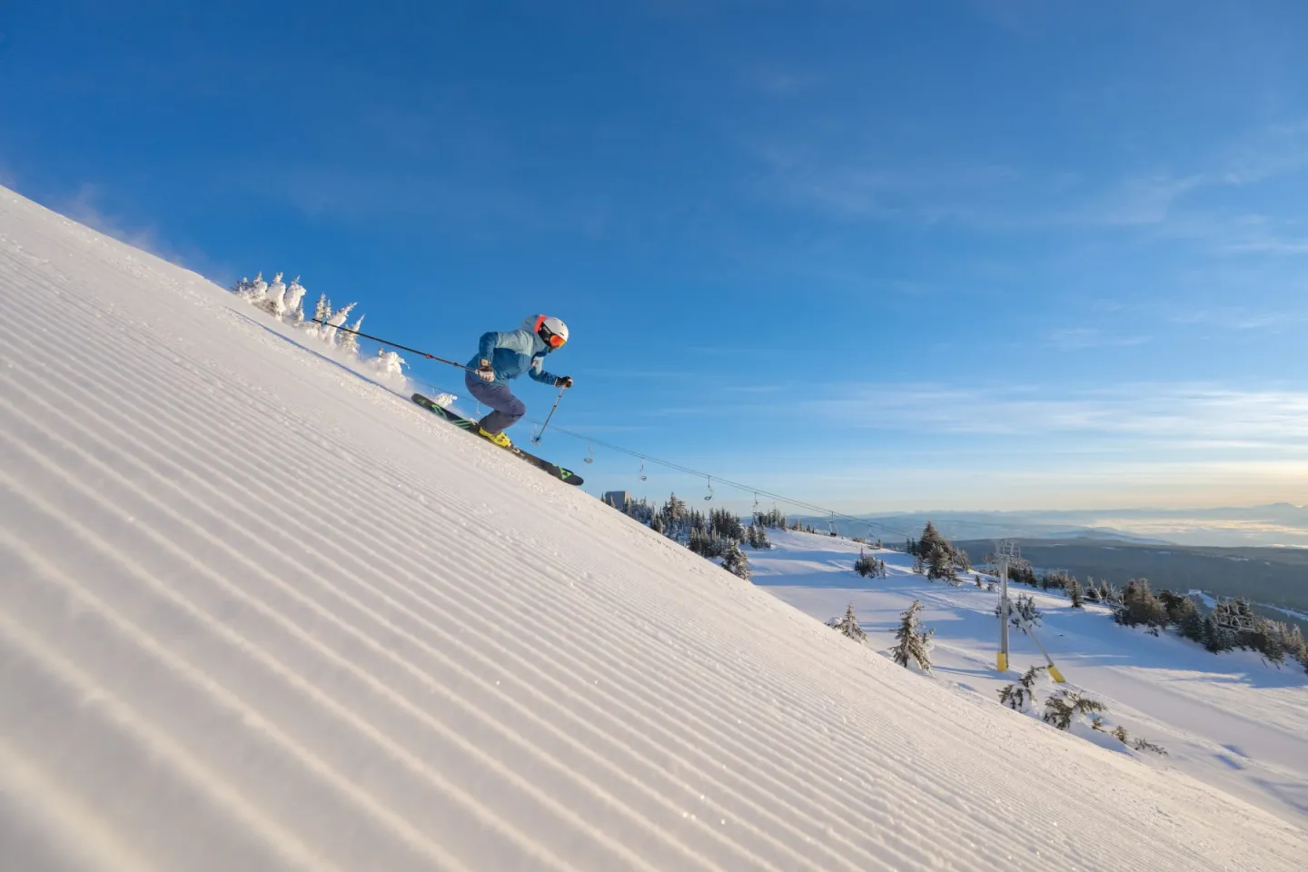 Skier jumping over a snowy slope under a bright blue sky.